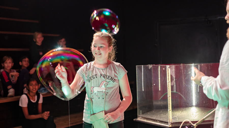 A girl is looking at soap bubbles