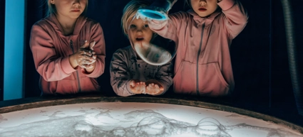 Tre små flickor leker med såpbubblor.
