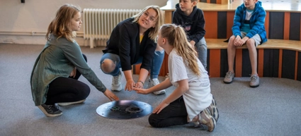 En grupp barn som sitter på golvet och leker med ett blåshål.