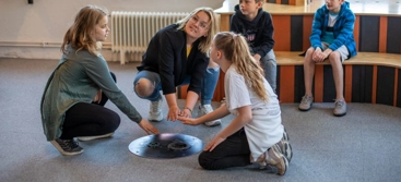 En grupp barn som sitter på golvet och leker med ett blåshål.