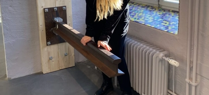 En kvinna står framför ett fönster och håller i en balk som sitter fast i väggen.