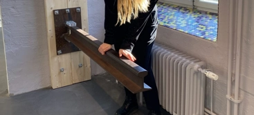 En kvinna står framför ett fönster och håller i en balk som sitter fast i väggen.