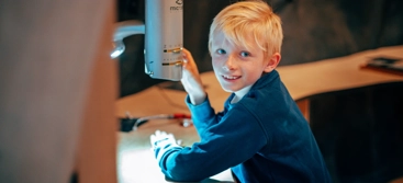 A young boy holding a microscope in his hand.