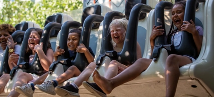 A group of people riding in roller coaster drop down