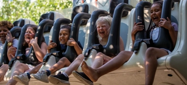 A group of people riding in roller coaster drop down