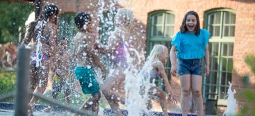 A group of children playing in a water fountain.