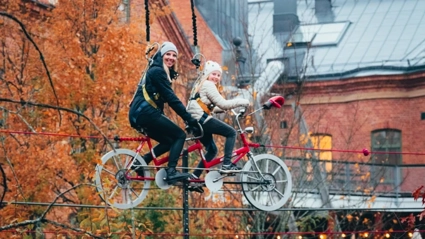 Föralder och barn cyklar på en lina