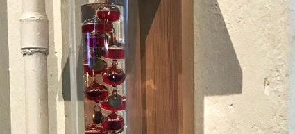 A wooden shelf with a glass bottle filled with red liquid on it.