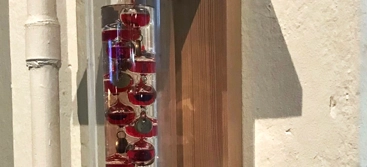 A wooden shelf with a glass bottle filled with red liquid on it.