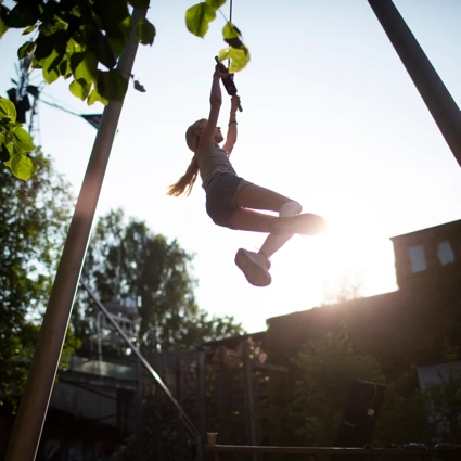 A young girl is swinging on a rope.