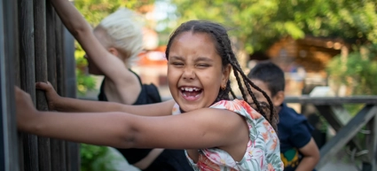 A young girl smiles as she holds on to a fence in the storm