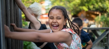 A young girl smiles as she holds on to a fence in the storm
