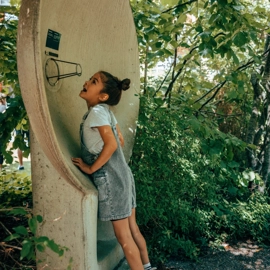 A young girl laughing while standing next to a parabola.