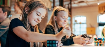 Two girls playing a game of rube cubes.