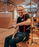 En glad man sitter på ett träbord.