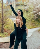 En glad flicka sitter på ryggen på en annan glad flicka