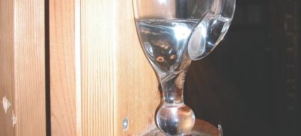 A glass water pitcher on a wooden shelf.