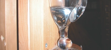 A glass water pitcher on a wooden shelf.