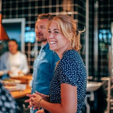 A man and a laughing woman standing in a kitchen.