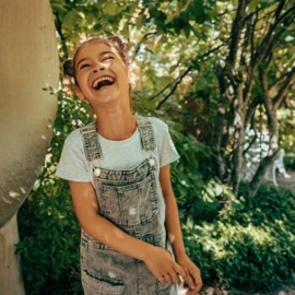 A young girl laughing while standing next to a parabola.