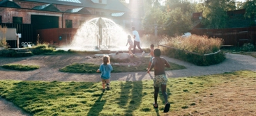 A group of people running into a fountain.