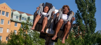 A couple of people riding on top of a roller coaster.