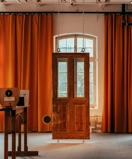 A room with orange curtains and a wooden door.