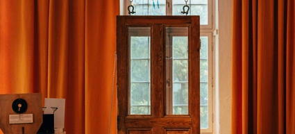 A room with orange curtains and a wooden door.