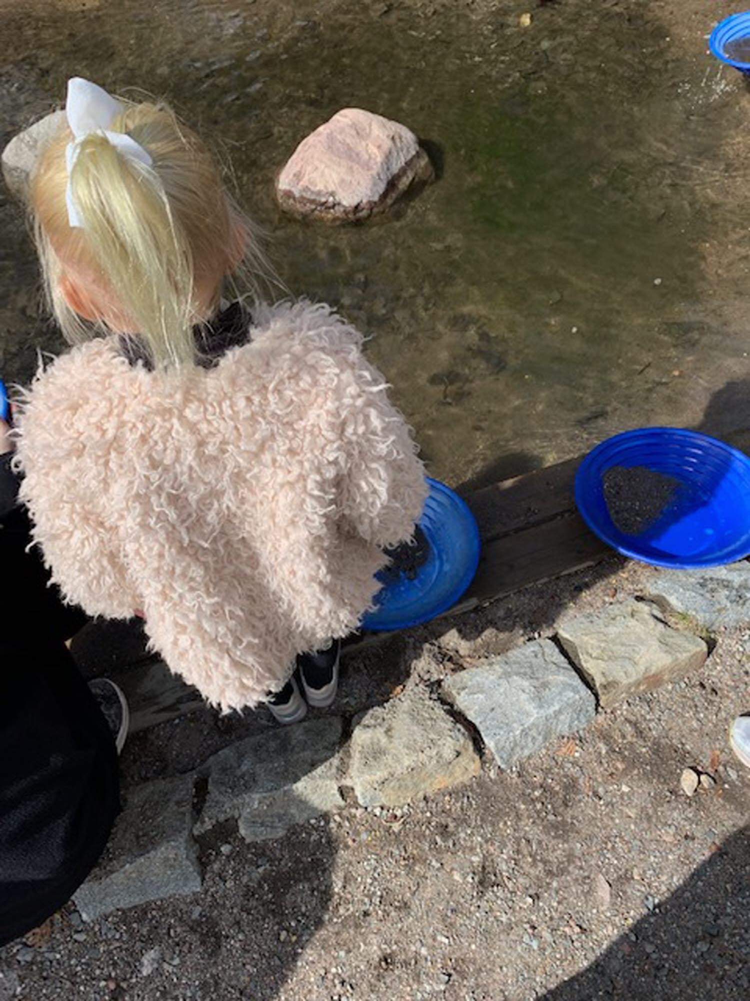 Tjej står vid vatten med blåa guldvaskare Tjej står vid vatten med blåa guldvaskare