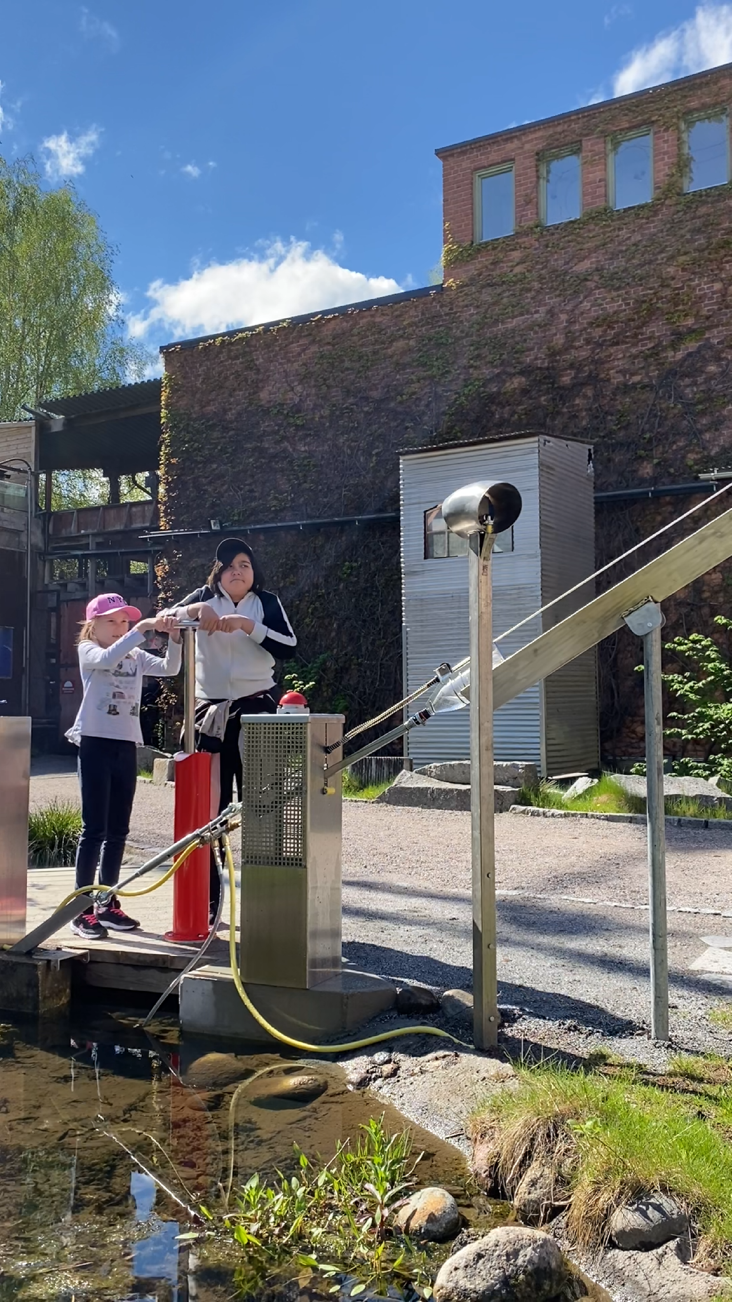 Två barn som pumpar upp tryck i vattenraketen Två barn som pumpar upp tryck i vattenraketen