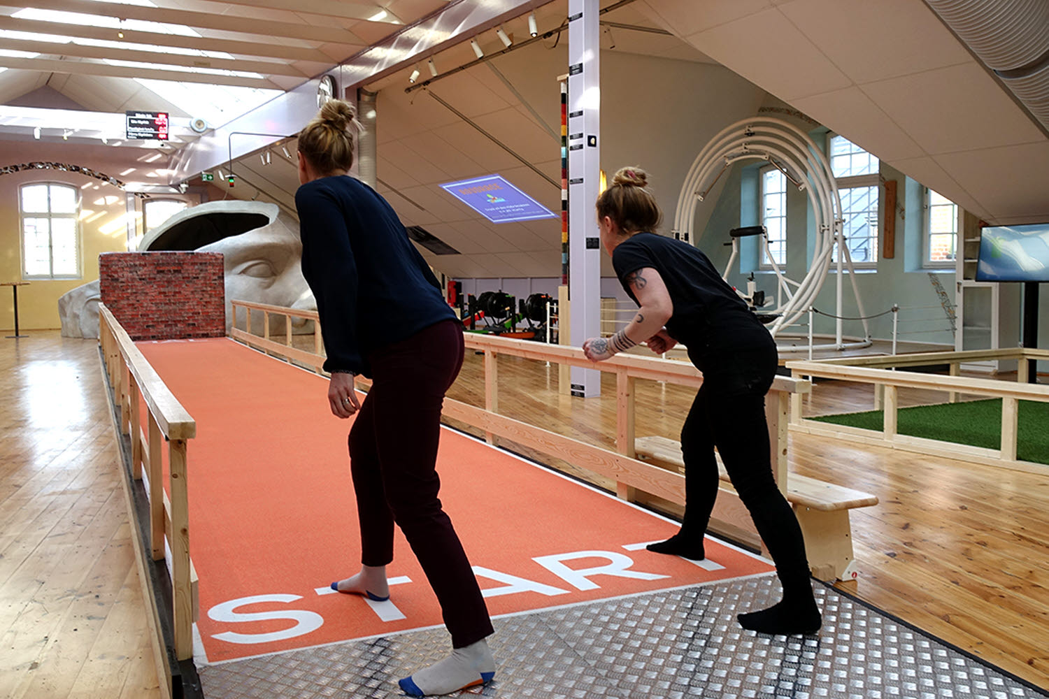 Två personer står vid startlinjen på en löparbana